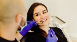 A woman sits in a dentist's examination chair while the dentist explains the smile makeover cost in India.